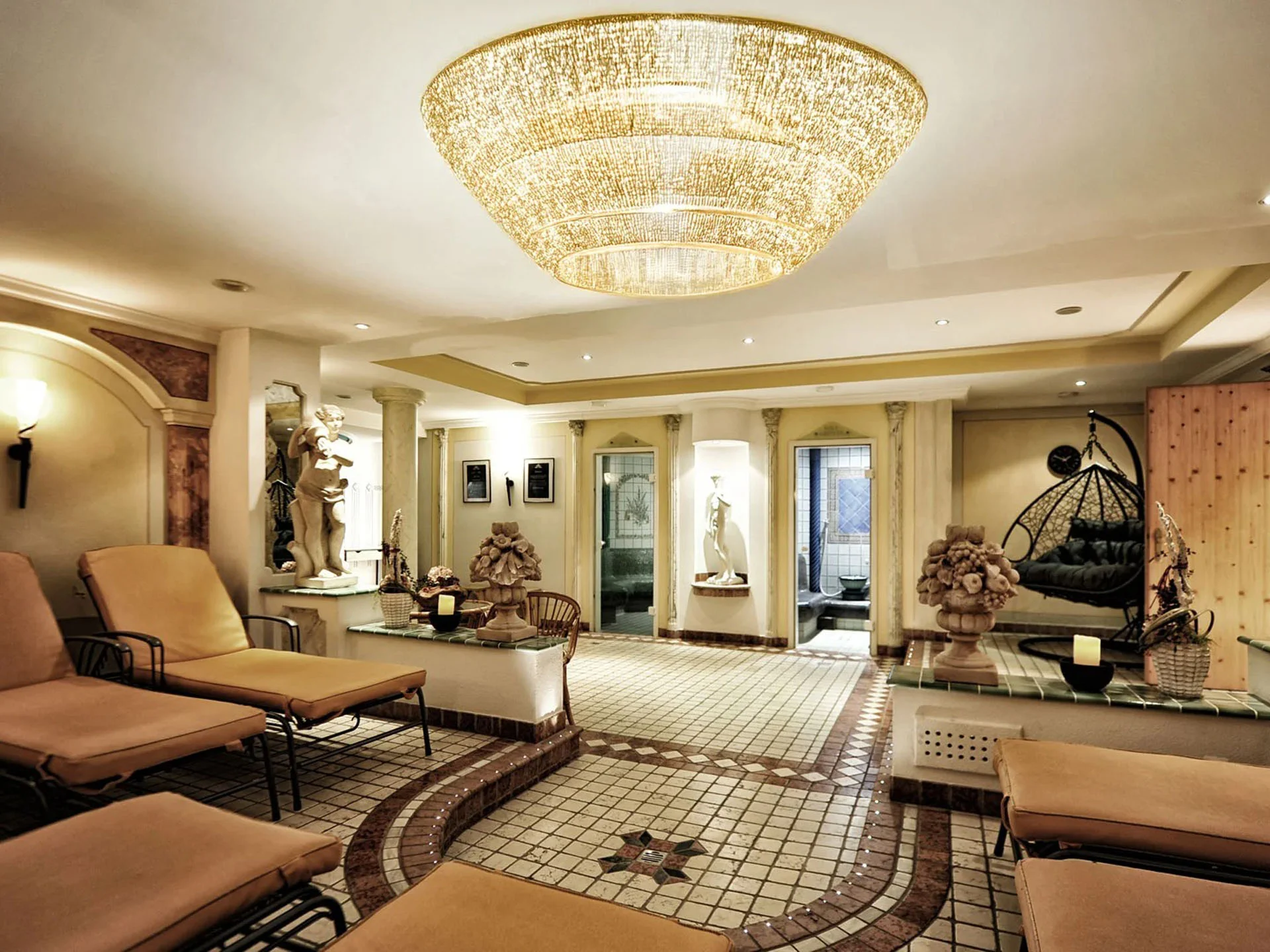 Die Bilder aus dem Hotel Salnerhof Eleganter Wellnessbereich mit Liegen, Statuen und großem Kronleuchter