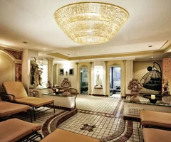 Ihr Wellnesshotel in Ischgl | Das Spa im Salnerhof Eleganter Wellnessbereich mit Liegen, Statuen und großem Kronleuchter