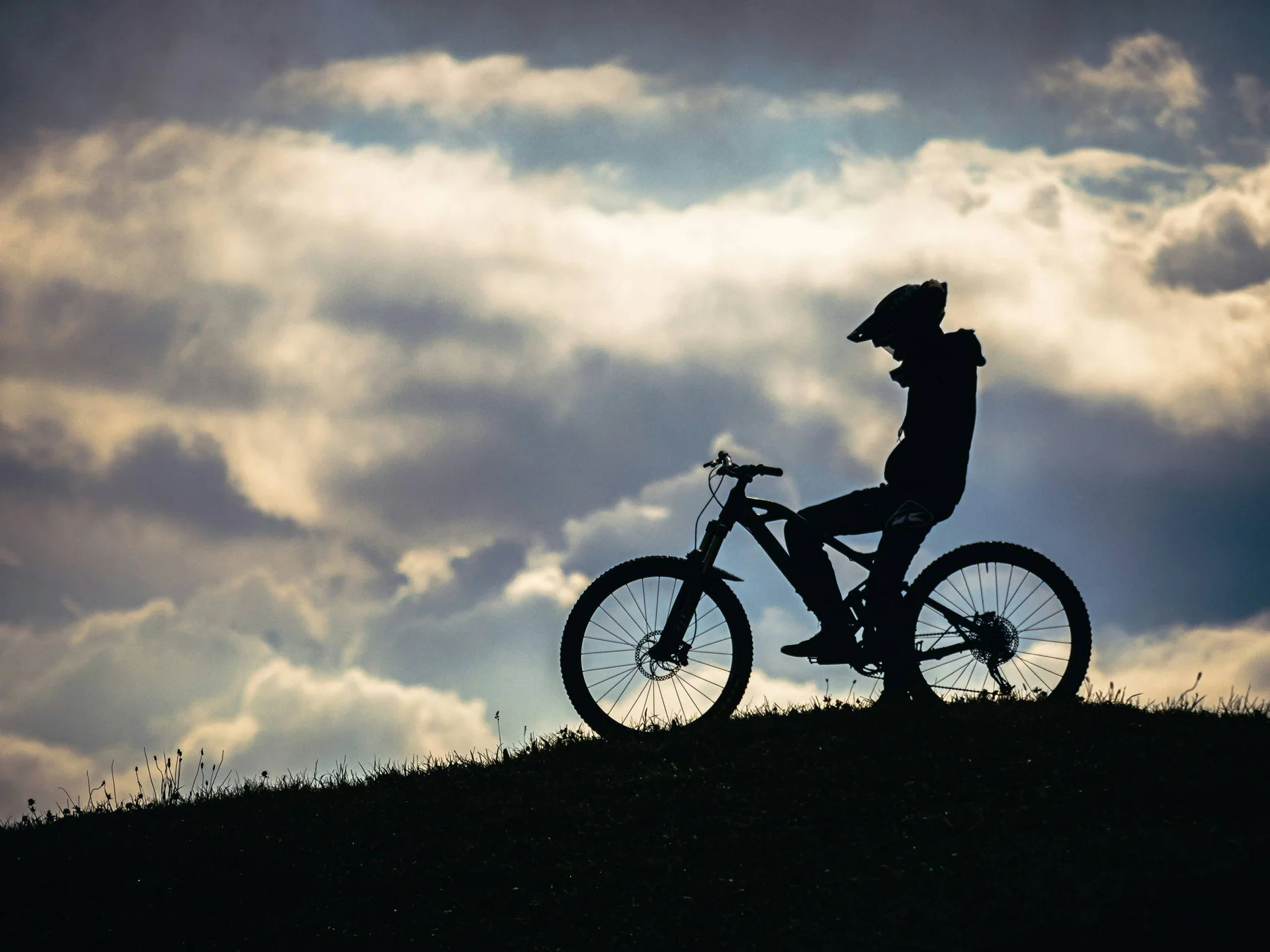 Die Bilder aus dem Hotel Salnerhof Silhouette eines Radfahrers mit Helm auf einem Hügel vor bewölktem Himmel