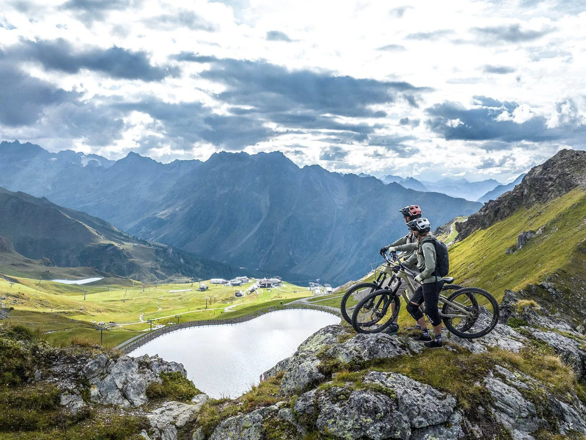 Die Bilder aus dem Hotel Salnerhof Zwei Mountainbiker auf einem Felsen mit Blick auf Bergsee und Alpenlandschaft