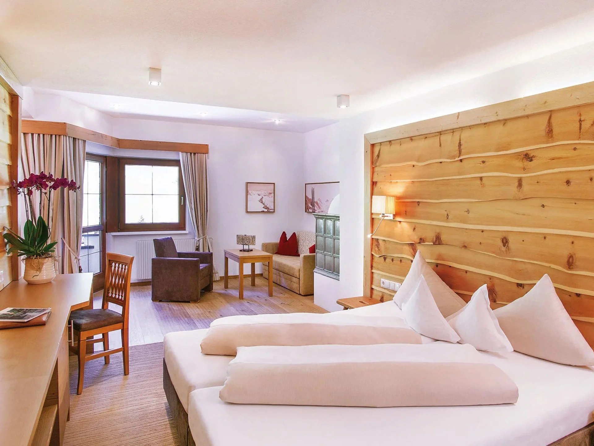 Die Bilder aus dem Hotel Salnerhof Gemütliches Hotelzimmer mit Holzwand, Doppelbett und Sitzbereich am Fenster