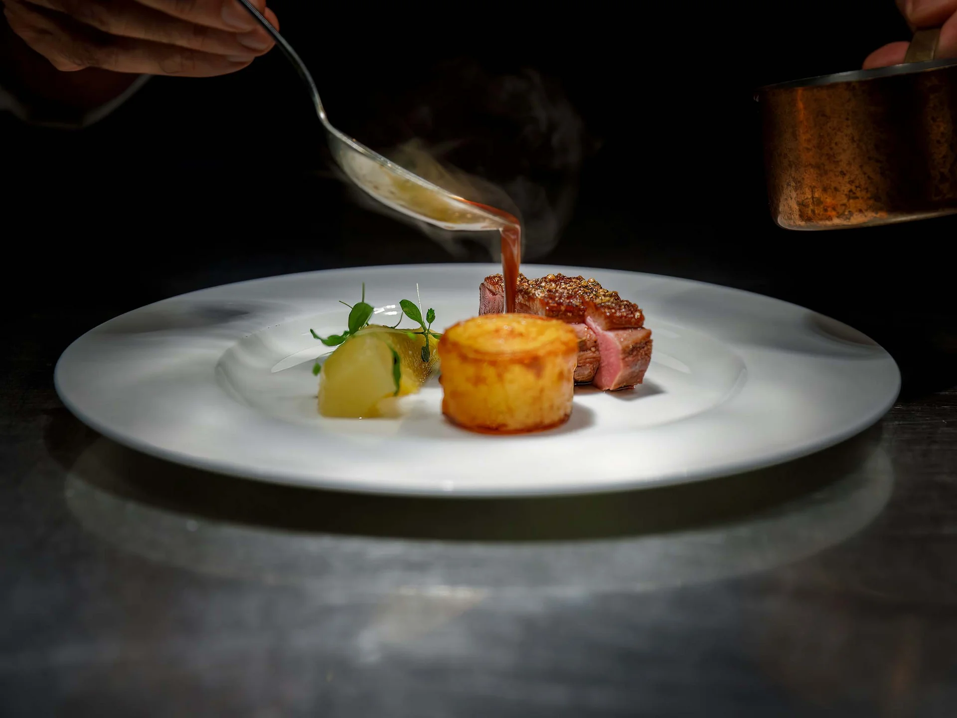 Die Bilder aus dem Hotel Salnerhof Soße wird auf ein fein angerichtetes Gericht mit Fleisch und Beilage gegossen