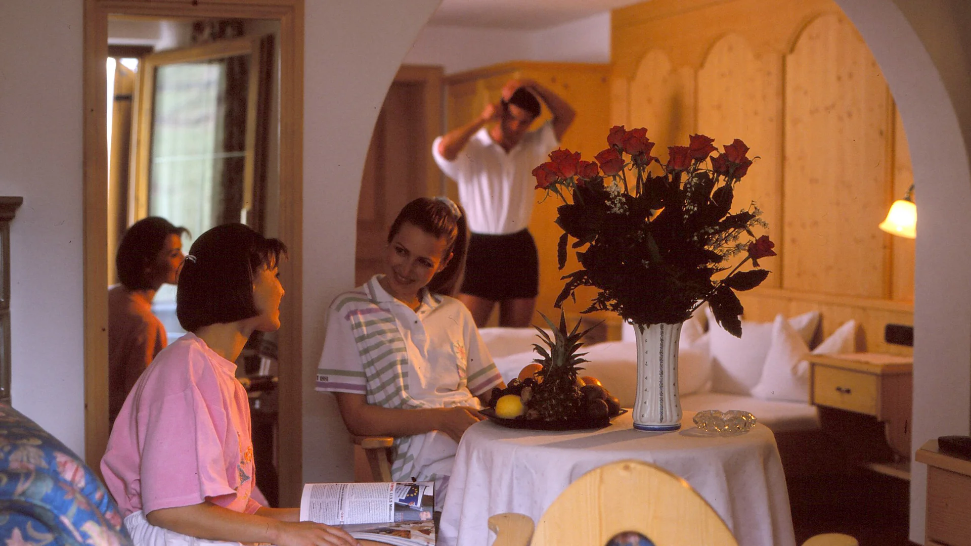 Die Geschichte des Salnerhofs Drei Frauen entspannen in einem gemütlichen Hotelzimmer mit Blumen und Obstteller