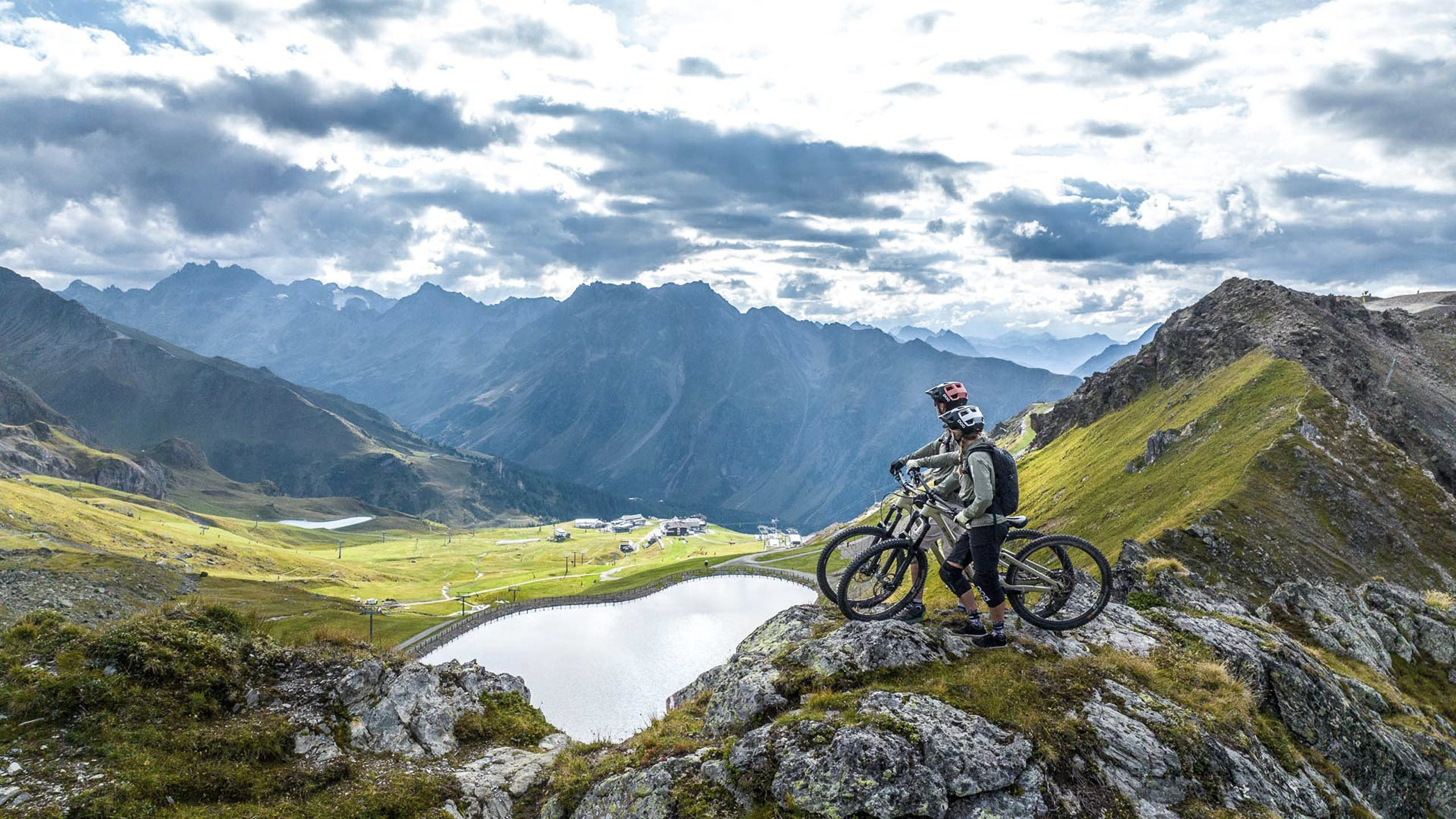 Die Bilder aus dem Hotel Salnerhof Zwei Mountainbiker auf einem Felsen mit Blick auf Bergsee und Alpenlandschaft