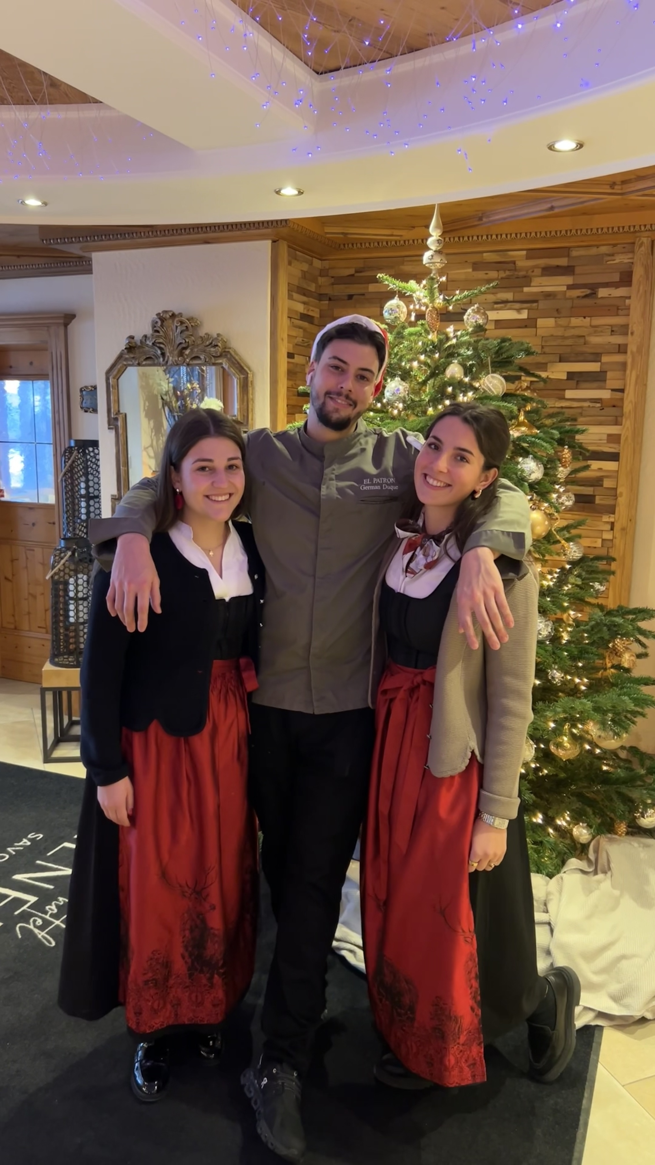 Dein Job im Salnerhof Drei Personen in traditioneller Kleidung vor einem geschmückten Weihnachtsbaum