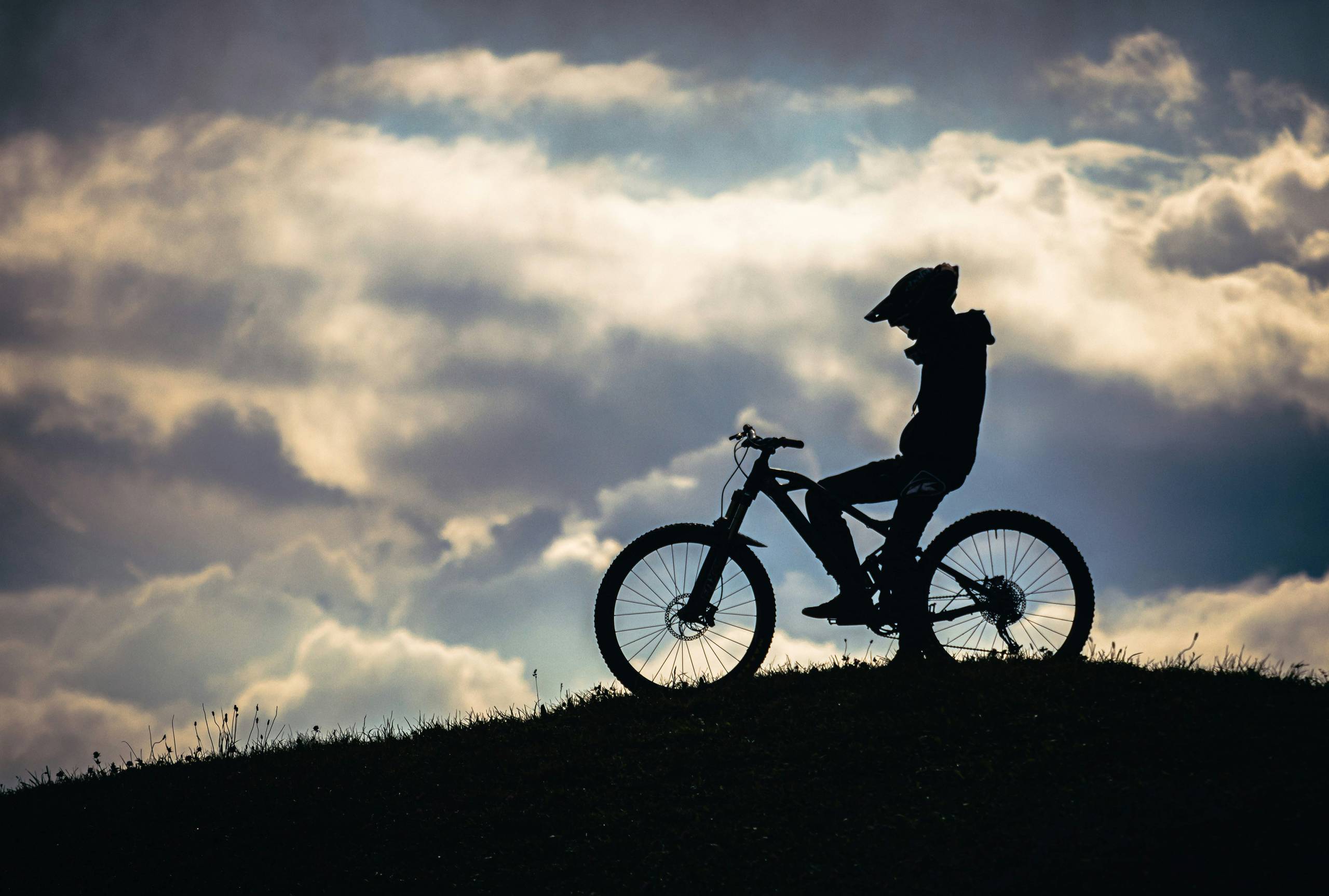 Die Bilder aus dem Hotel Salnerhof Silhouette eines Radfahrers mit Helm auf einem Hügel vor bewölktem Himmel