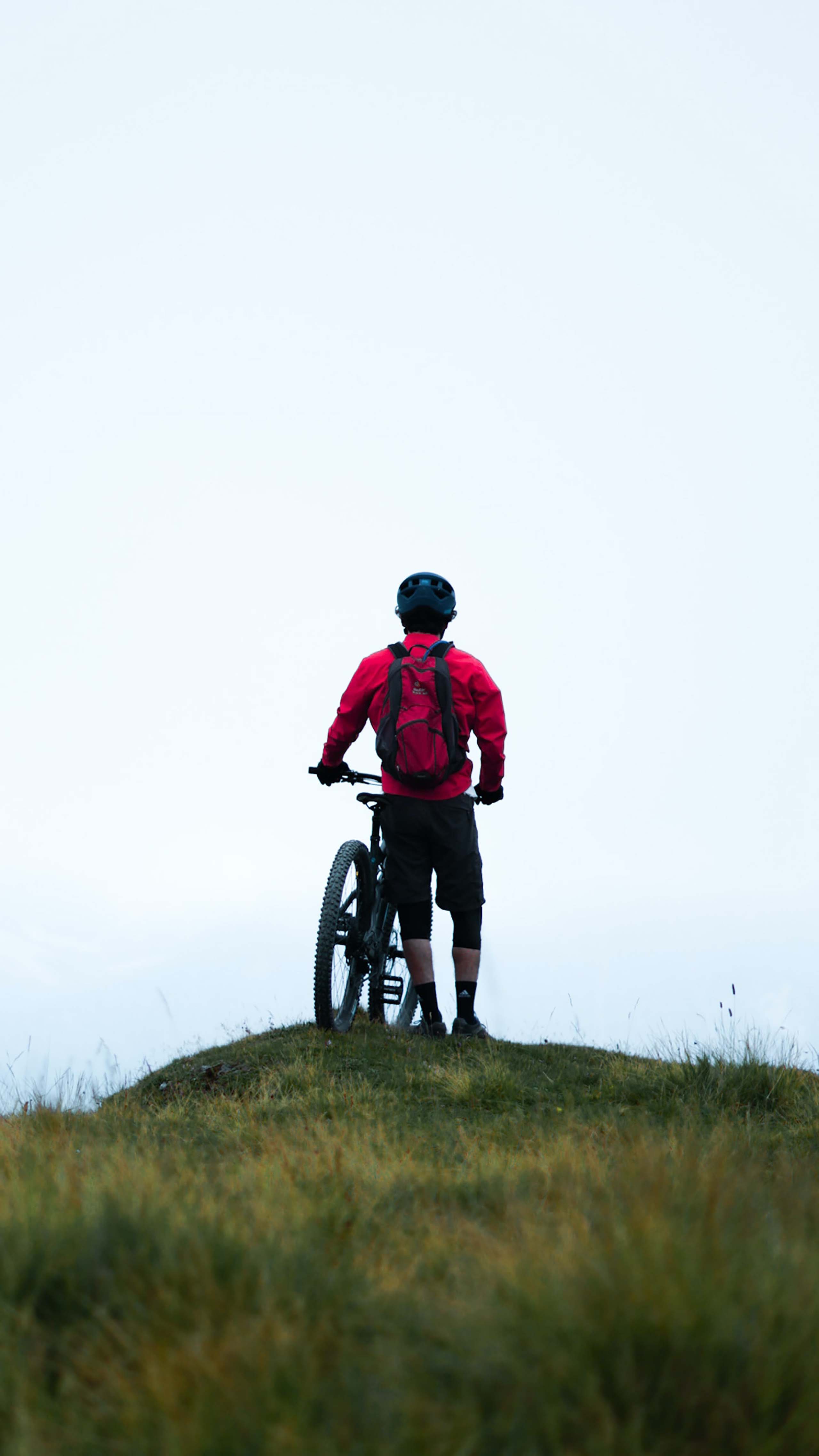 Die Bilder aus dem Hotel Salnerhof Mountainbiker mit rotem Rucksack steht auf Hügel mit Fahrrad