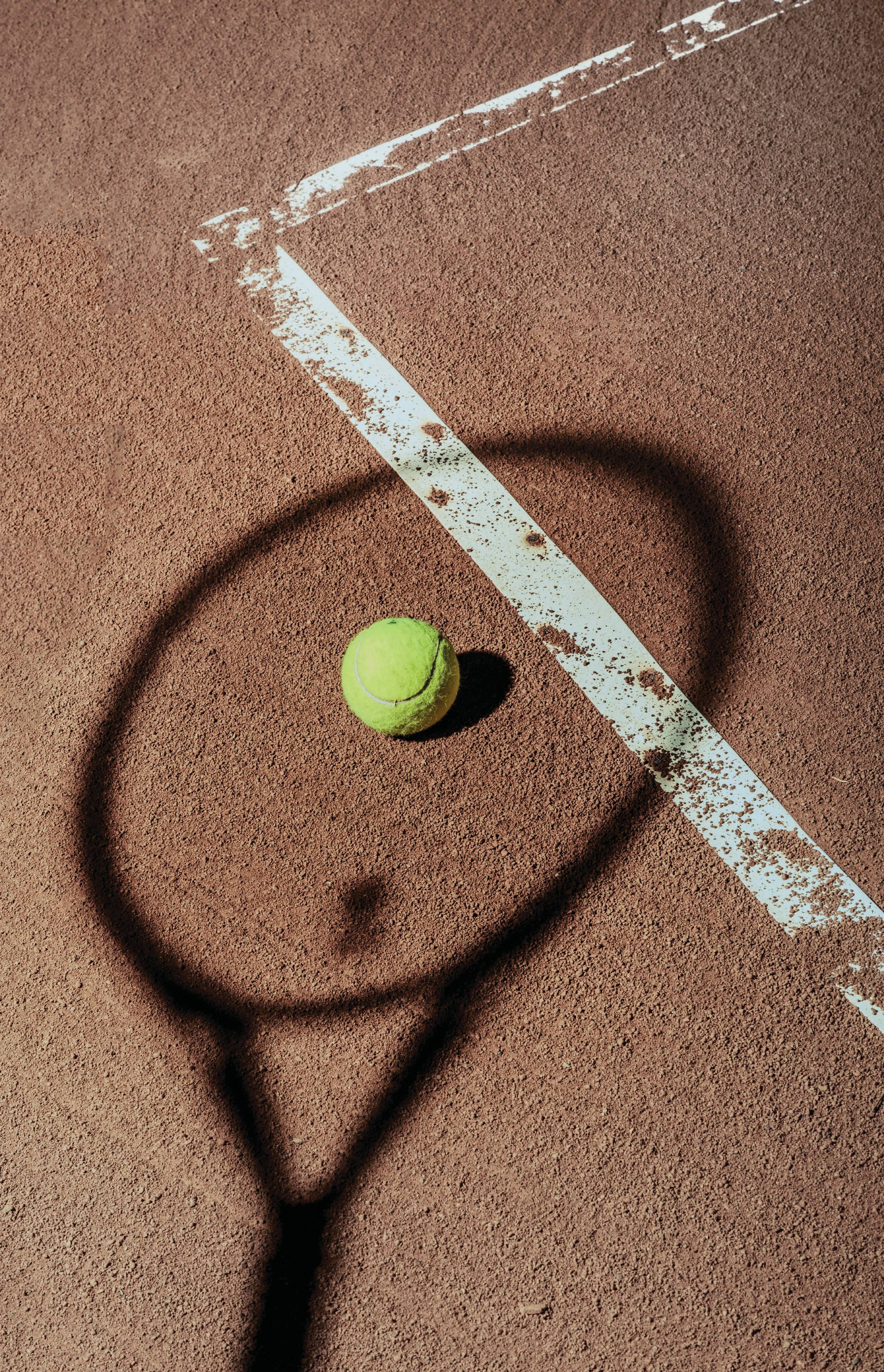 Die Bilder aus dem Hotel Salnerhof Schatten eines Tennisschlägers und ein Tennisball auf einem Sandplatz